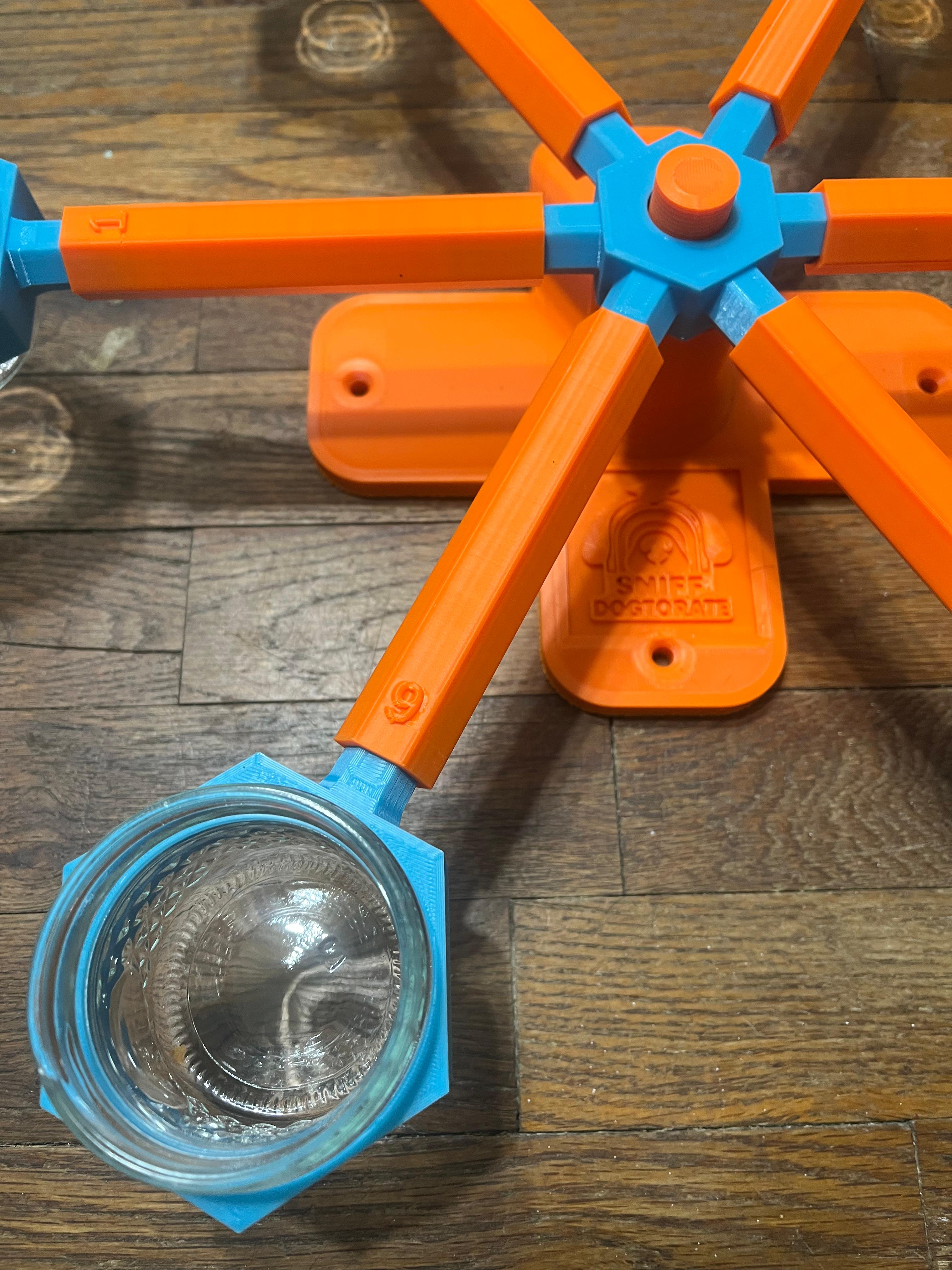 Photo is a close of up assembled orange and blue wheel, showing detail on the number on the arm and how the glass cup holders fit into the scent wheel arms.