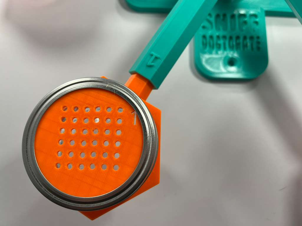 Orange and teal scent wheel with orange scent cover cups, discs that have a grid of small holes to allow odor through