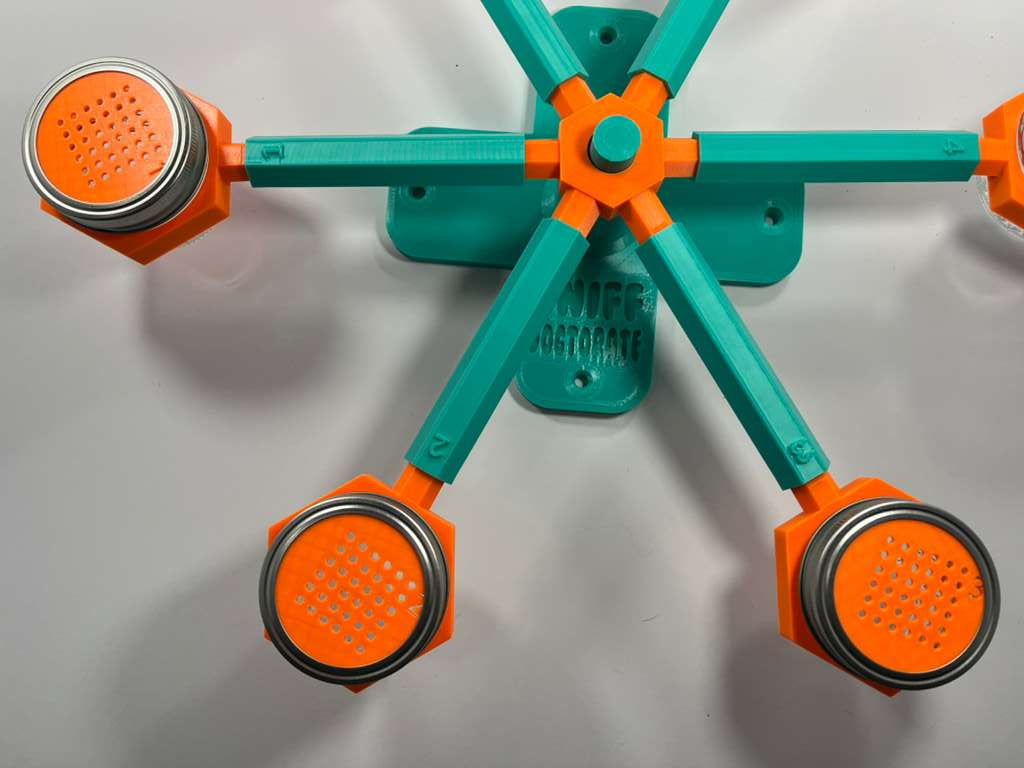 Orange and teal scent wheel with orange scent cover cups, discs that have a grid of small holes to allow odor through