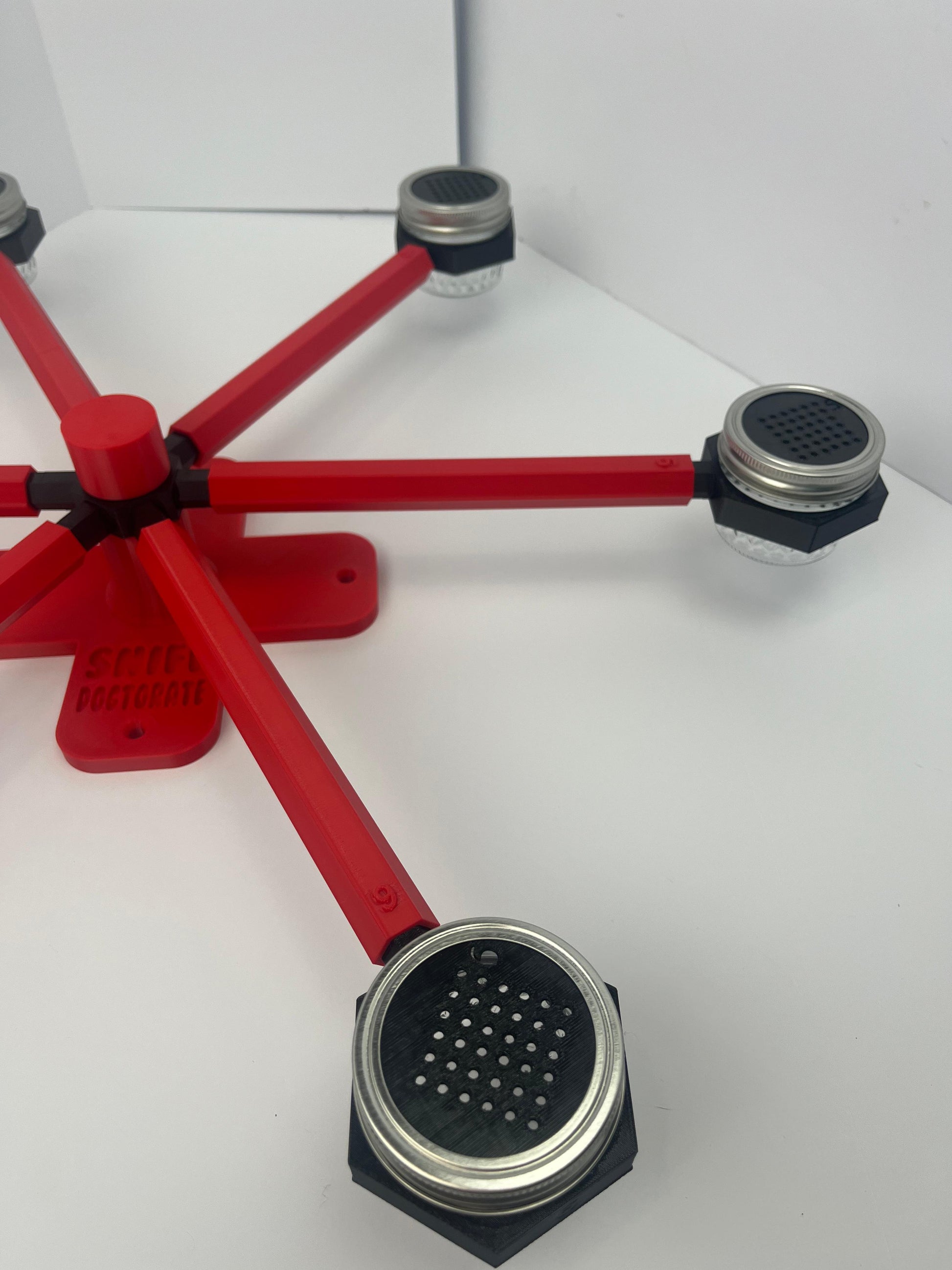 Large scent wheel with red base and arms and black spinner, cup holders, cup covers, and base topper